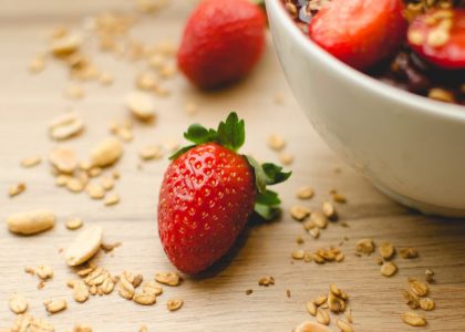 A close-up of a fresh strawberry breakfast bowl with granola on a wooden table, highlighting health and nutrition.